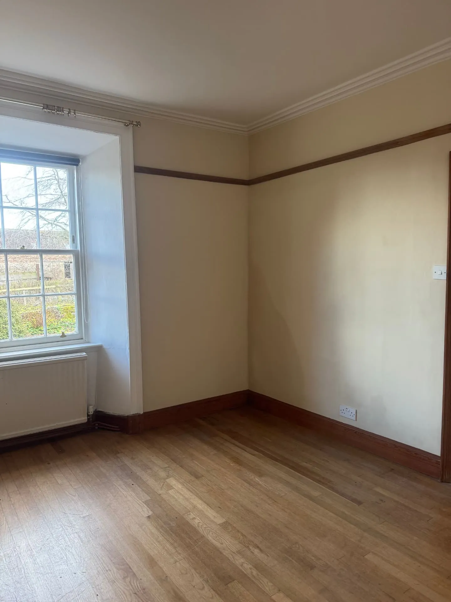 Finished bedroom in a Midlothian home, soft cream walls with white sash window and varnished picture rail
