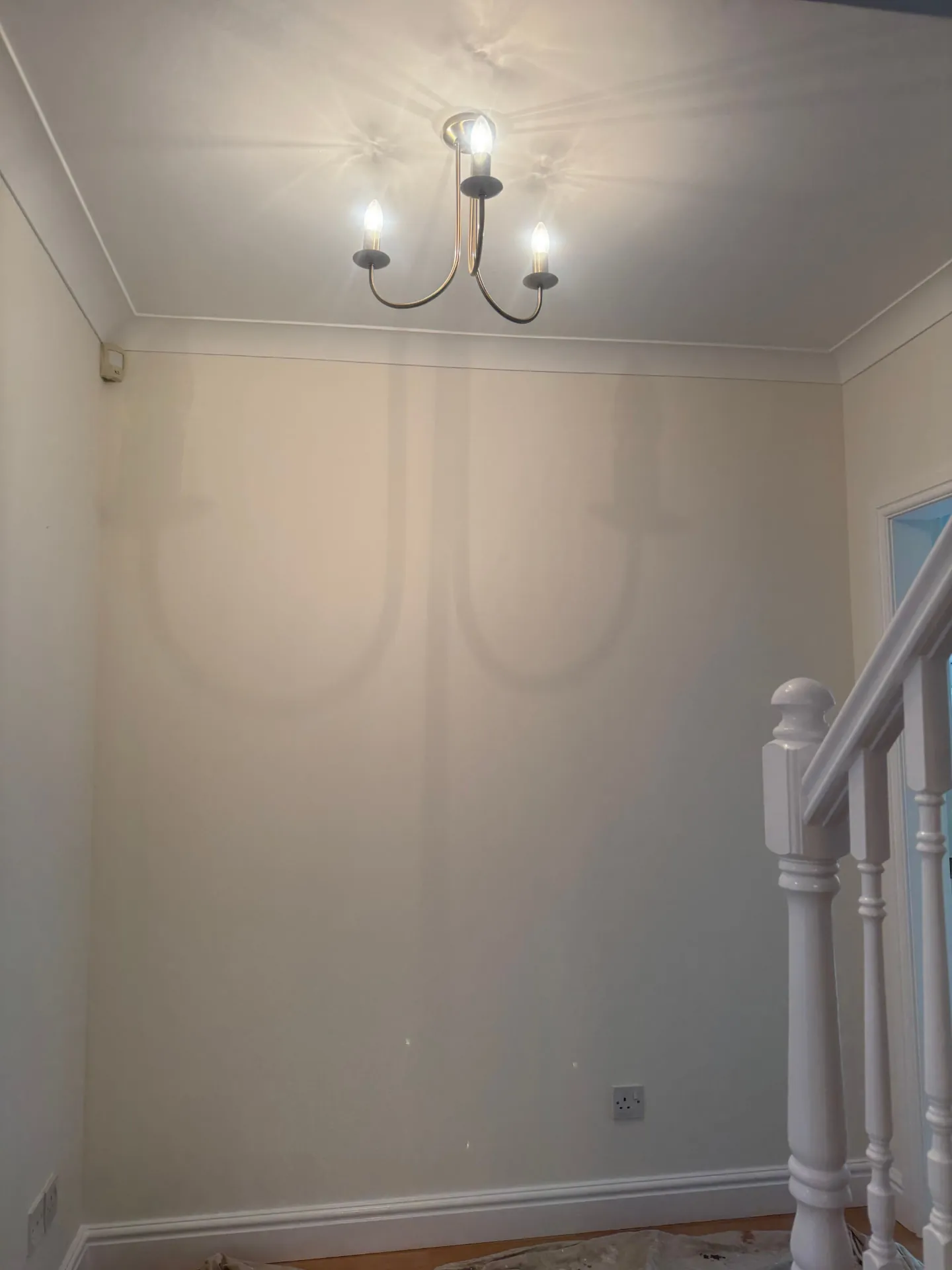 Tall stairwell wall in a Midlothian home rolled out in warm off-white with a crisp cut line at the cornice
