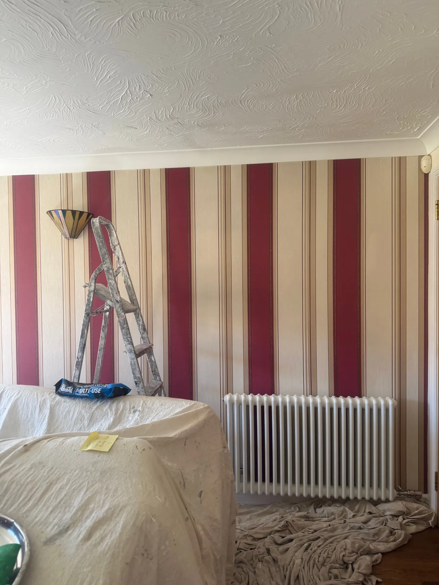 Red, gold and cream striped wallpaper hung in an Edinburgh home by W J Crighton, above a white column radiator
